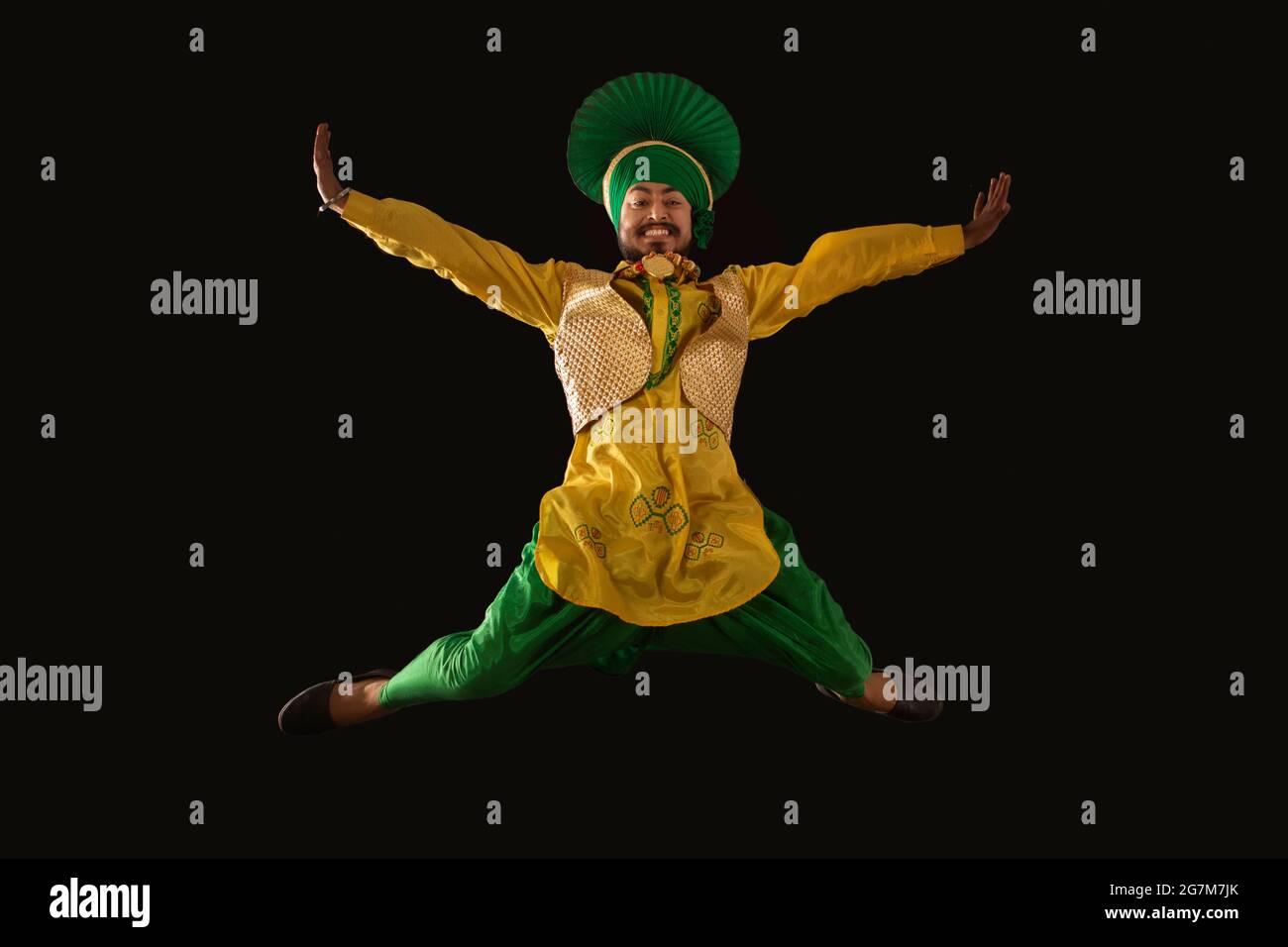 A Bhangra Dancer jumping with hands stretched to perform a dance