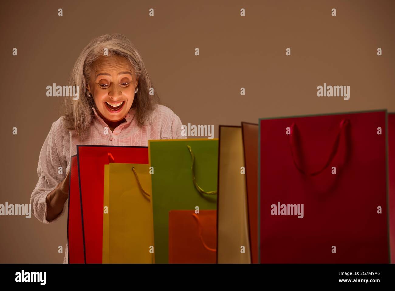 An old woman elated by looking into her Carry bags. Stock Photo