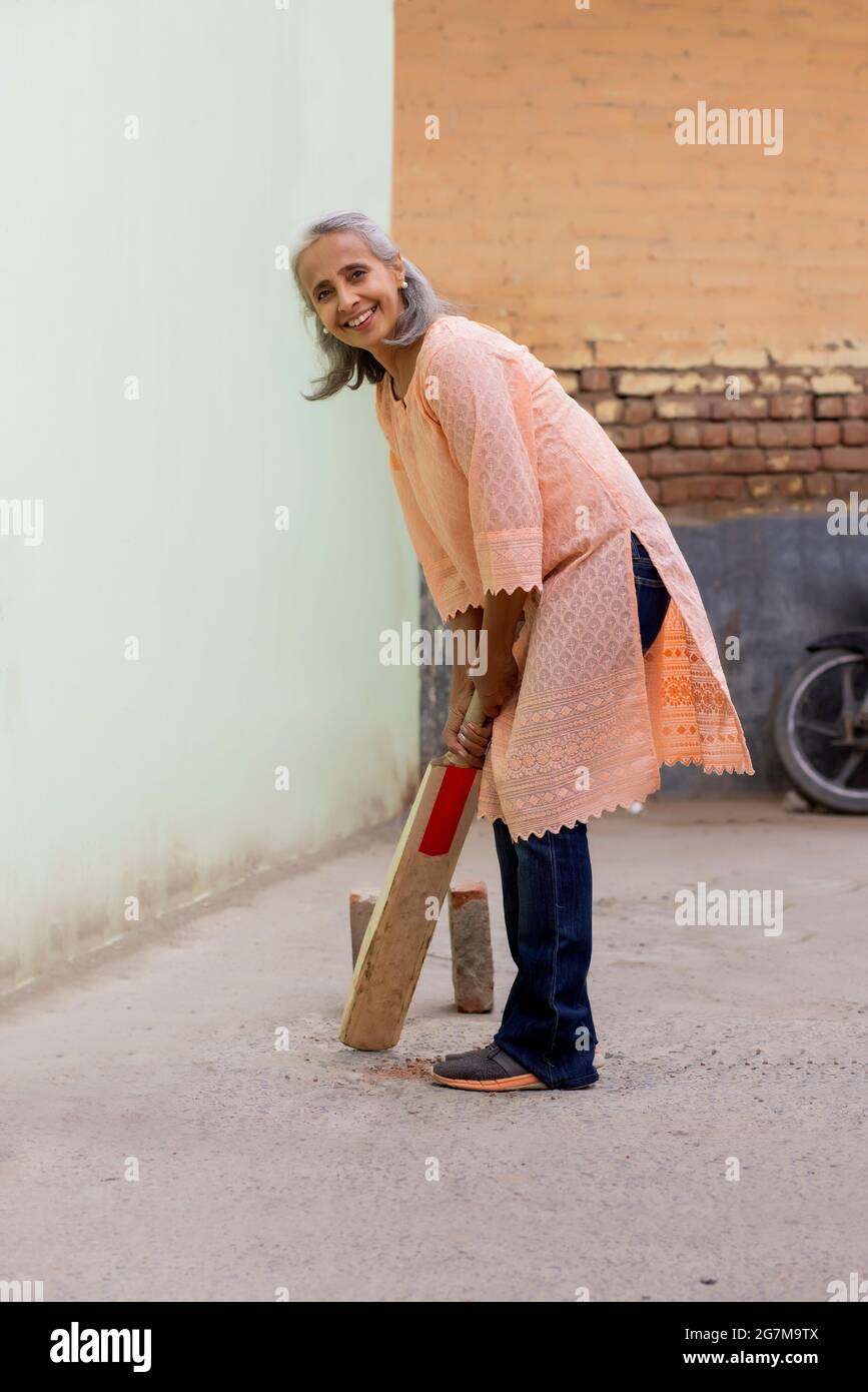 An old woman playing cricket ready to bat. Stock Photo
