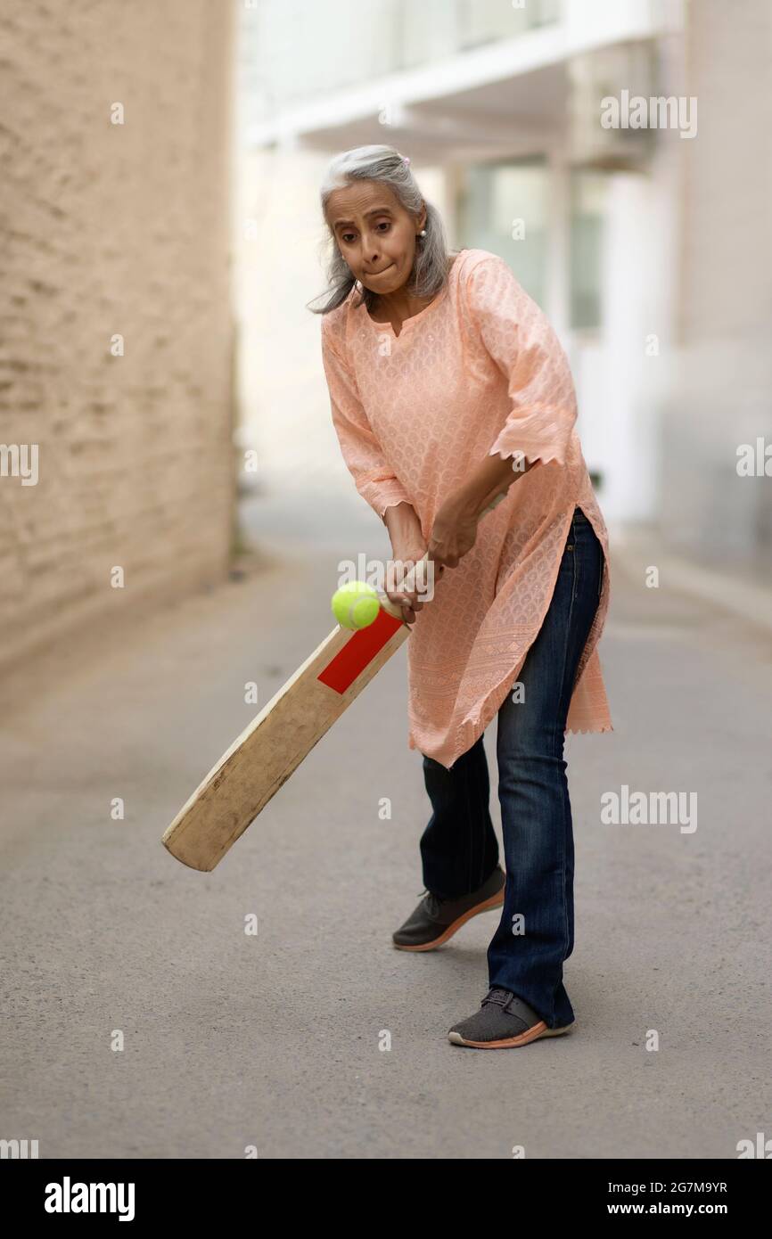 An old woman playing cricket. Stock Photo