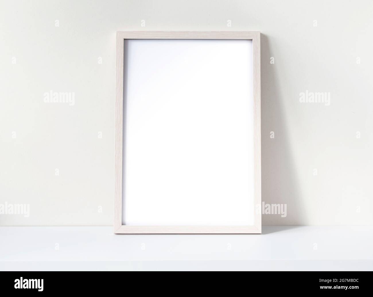 Photo frame mockup with white blank sheet on a white desk. Pine wooden frame mockup. Space for text. Stock Photo