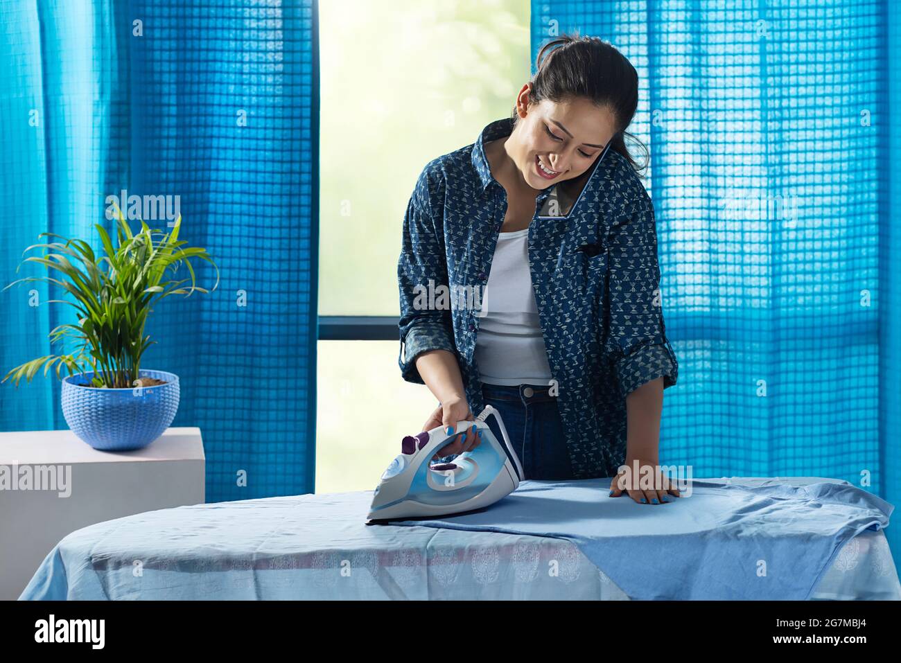 A woman ironing her clothes while talking on phone Stock Photo Alamy