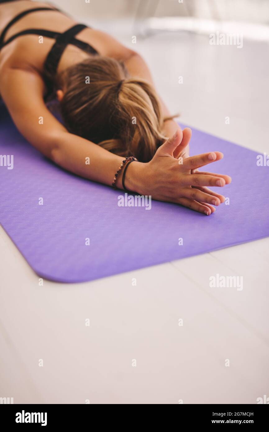 Female doing stretching workout on exercise mat. Woman doing balasana yoga at gym, with focus on hands. Stock Photo