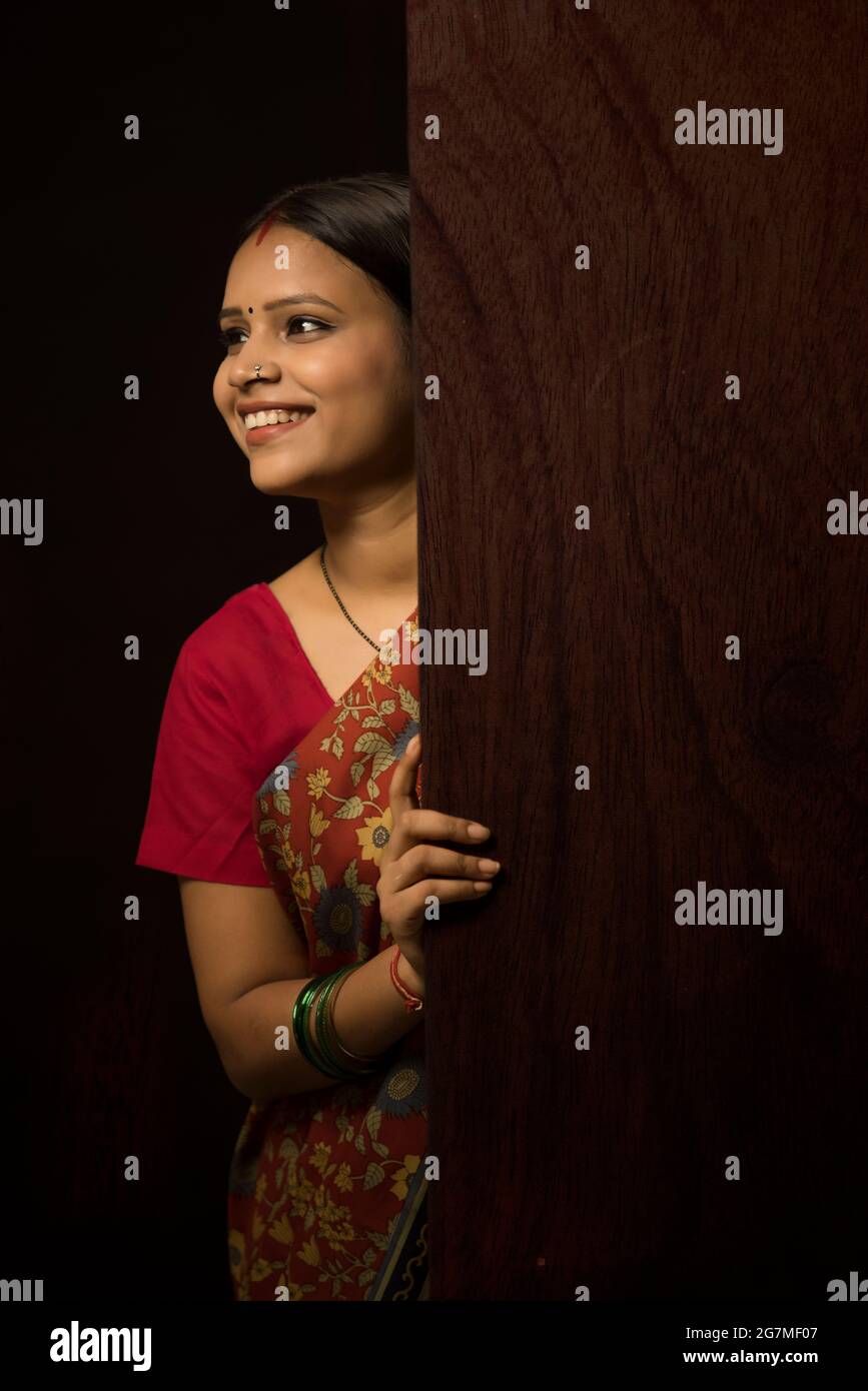 A HAPPY RURAL WOMAN STANDING BEHIND DOOR AND LOOKING AWAY Stock Photo ...