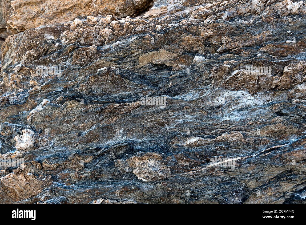 Dark Volcanic rock surface texture with colored spots. Rock formations