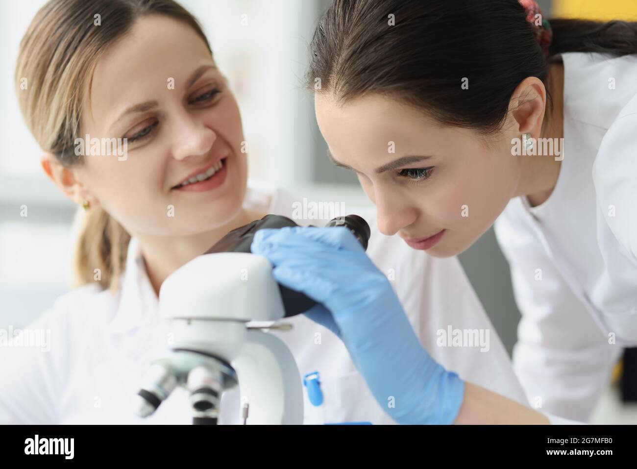 Female scientists chemists looking through microscope in laboratory Stock Photo