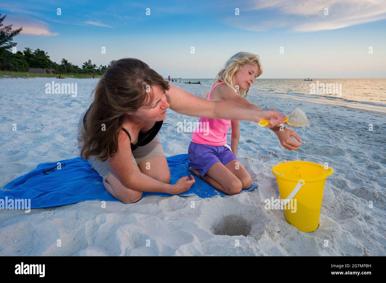 mother and daughter playing with sand on beach,Naples,Florida,USA Stock Photo