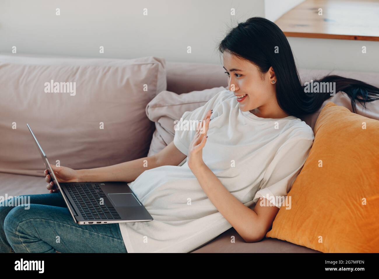 Portrait of asian woman enjoying using laptop at apartment interior indoor living room. Video call vlogger webinar stream concept Stock Photo