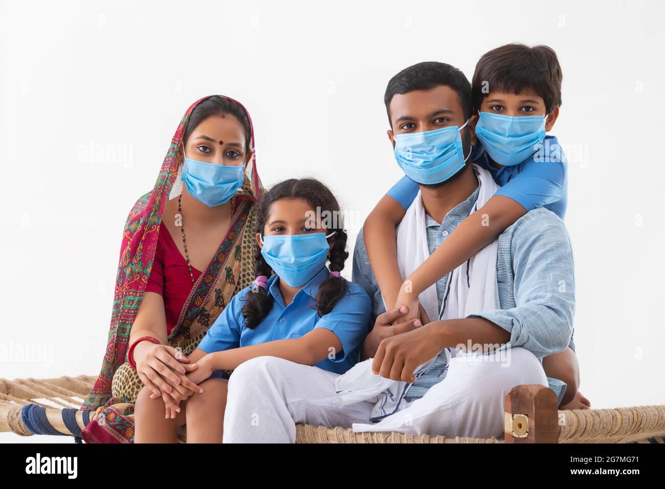 PORTRAIT OF A RURAL FAMILY WEARING MASKS AND LOOKING AT CAMERA Stock Photo