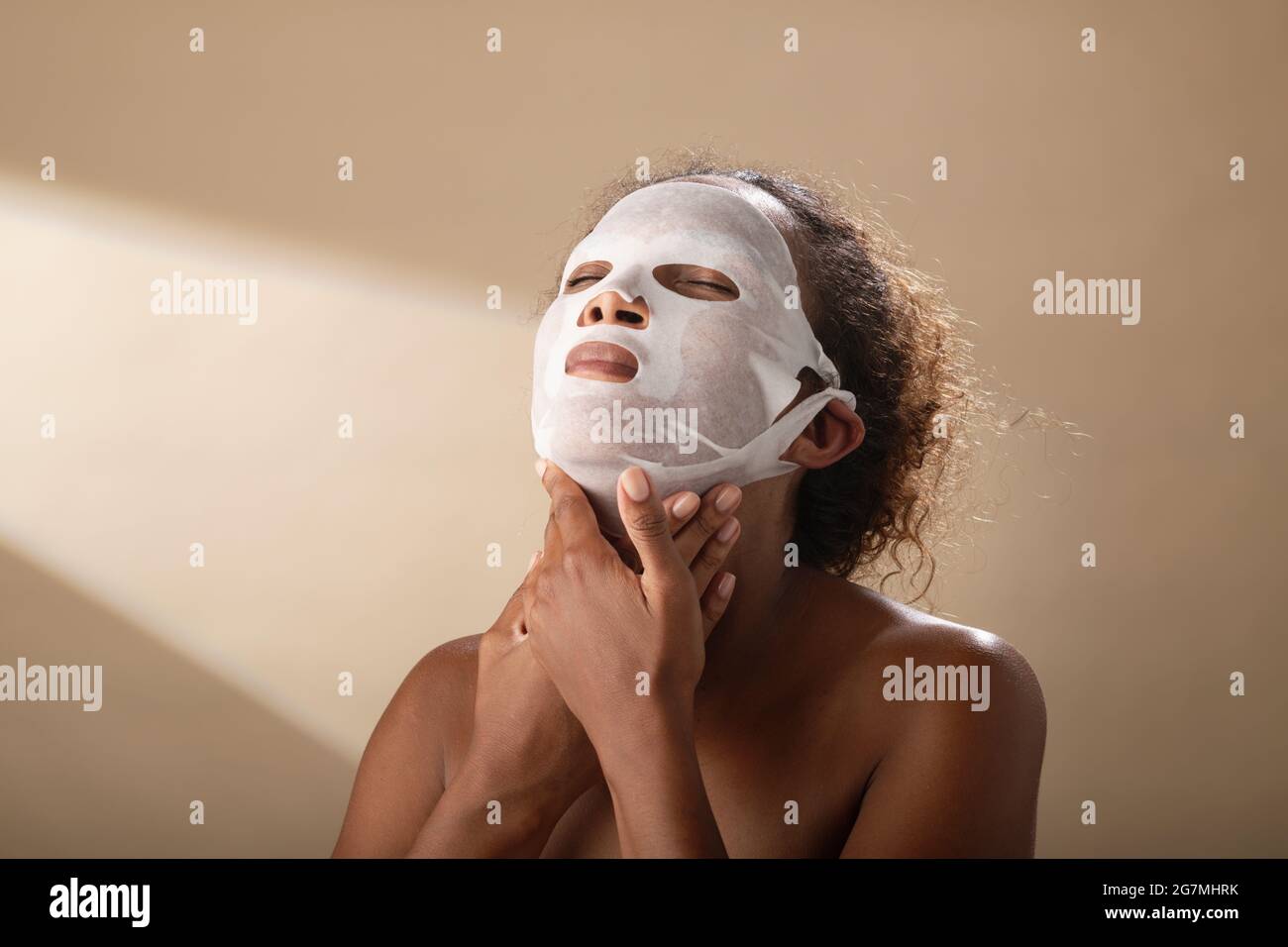 A woman applying a hydration face mask treatment at home. Stock Photo