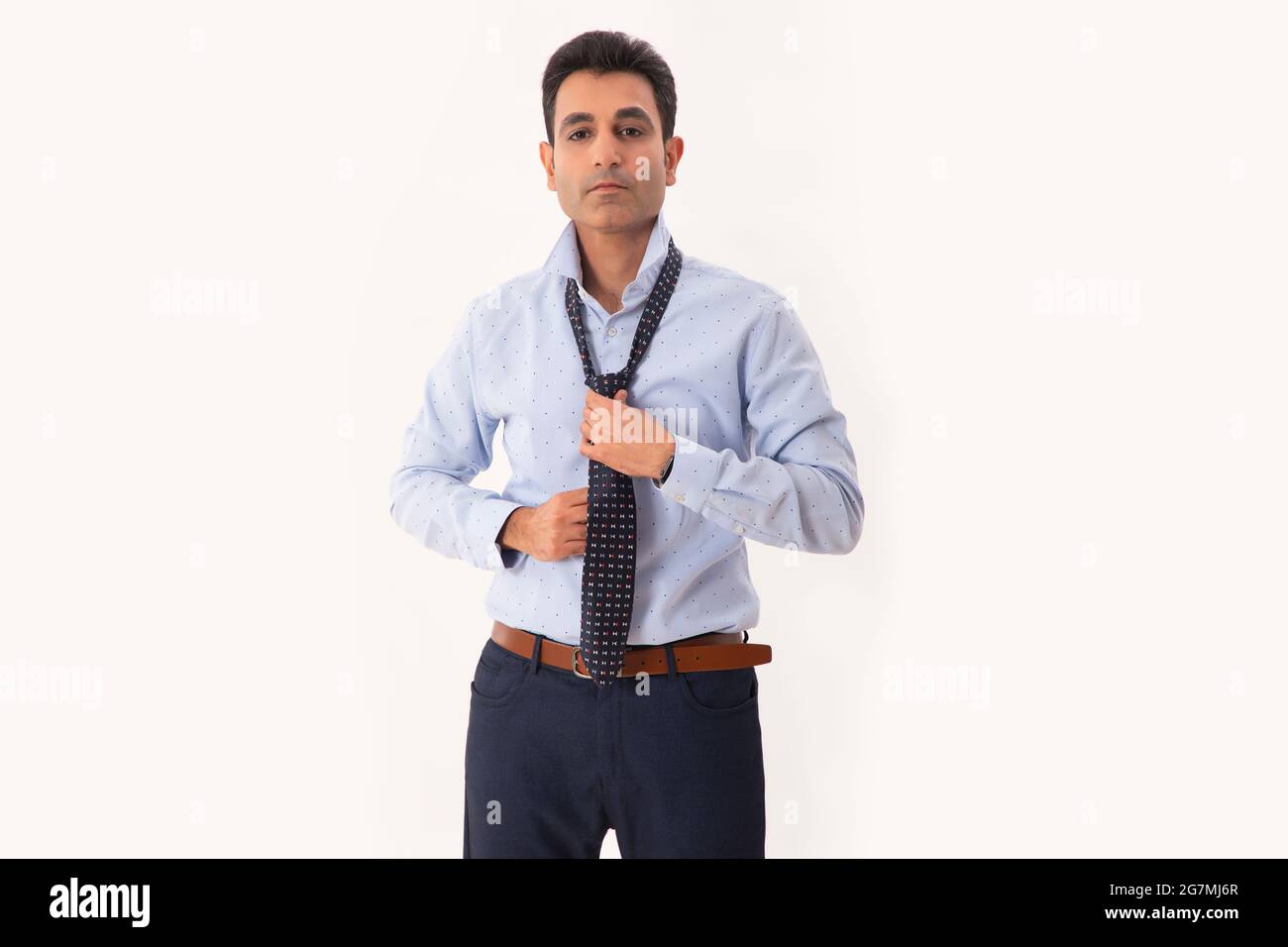 A CORPORATE PROFESSIONAL WEARING TIE WHILE STANDING IN FRONT OF CAMERA Stock Photo