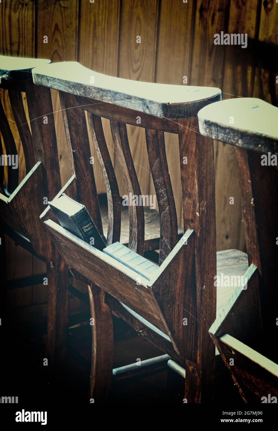 The common prayer book in the back of a wooden church congregation chair. Stock Photo