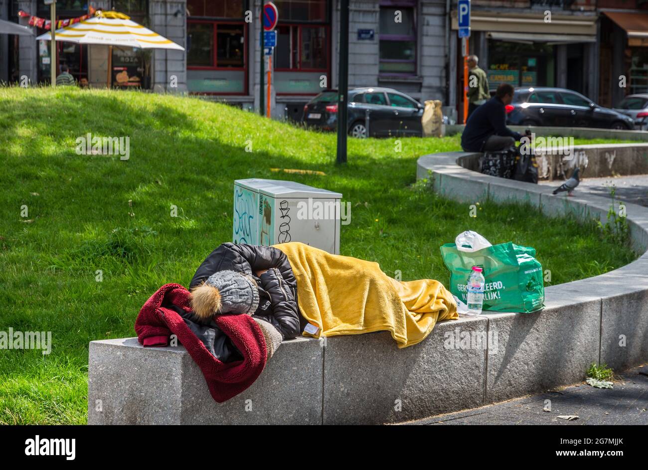 Homeless woman sleeping on city centre garden wall - Saint Gilles, Brussels, Belgium. Stock Photo