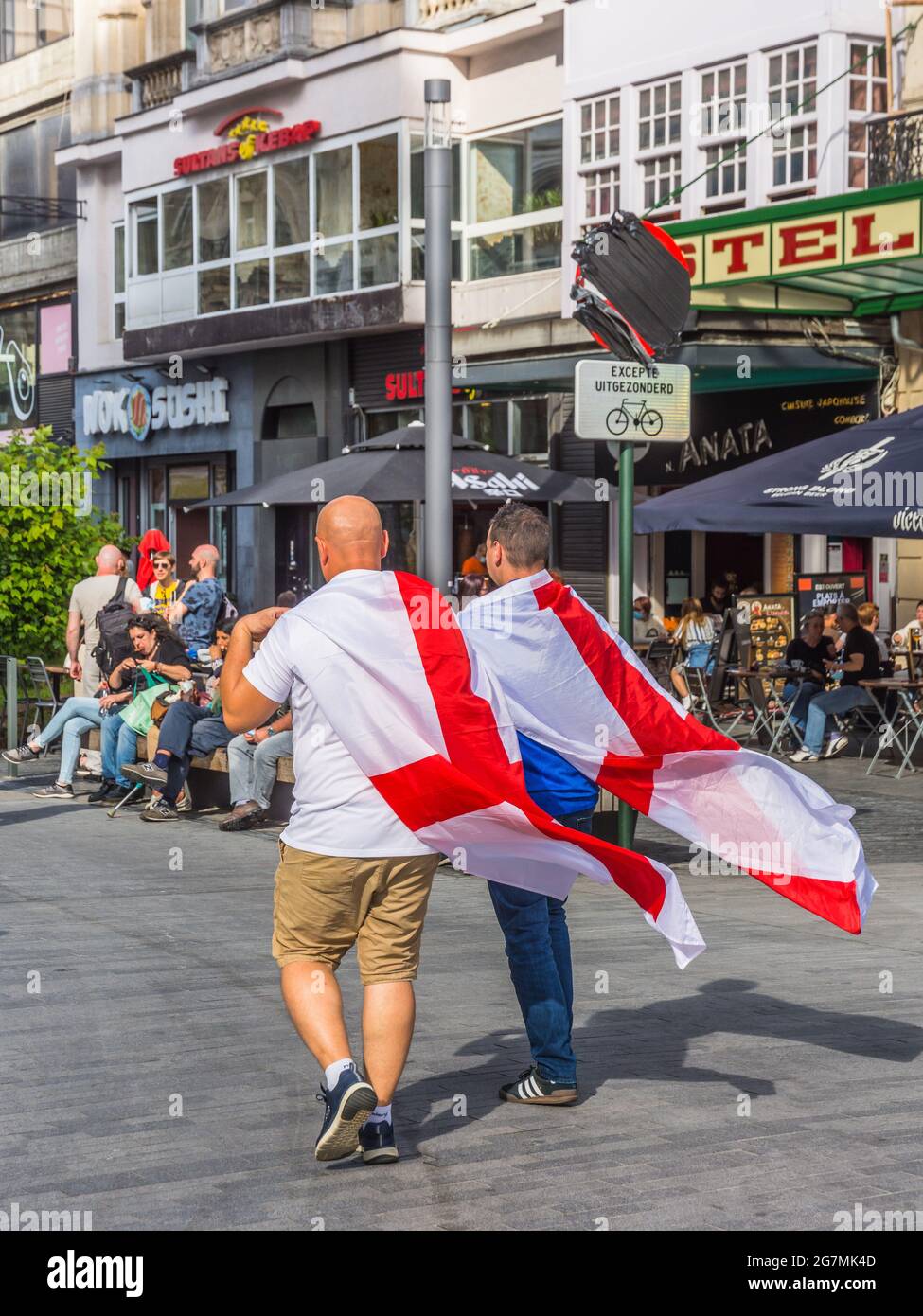 Two British Euro 2021 football supporters walking through Brussels city centre with St George's flag over shoulders Stock Photo