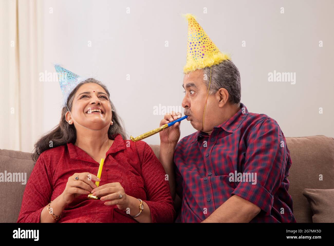 AN OLD MAN PLAYFULLY BLOWING TEASING WIFE WHILE CELEBRATING BIRTHDAY Stock Photo