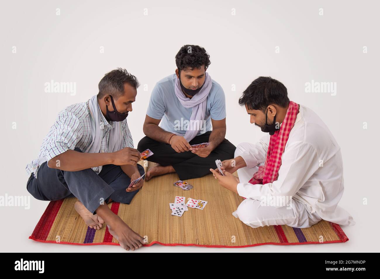 A GROUP OF COMMON MEN SITTING TOGETHER AND PLAYING CARDS Stock Photo
