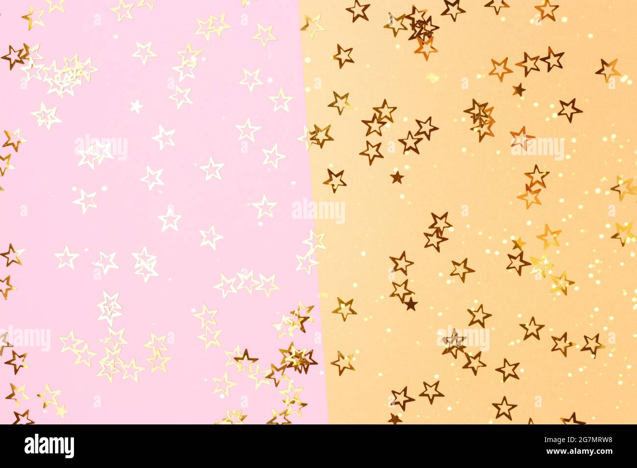 Bright glittering stars confetti scattered on a pink and gold ...