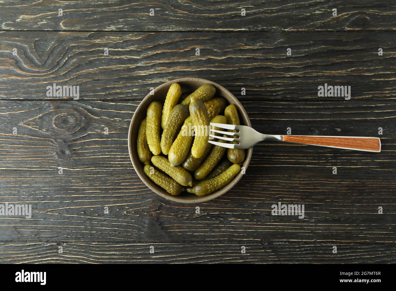 Bowl of pickles and fork on wooden background Stock Photo