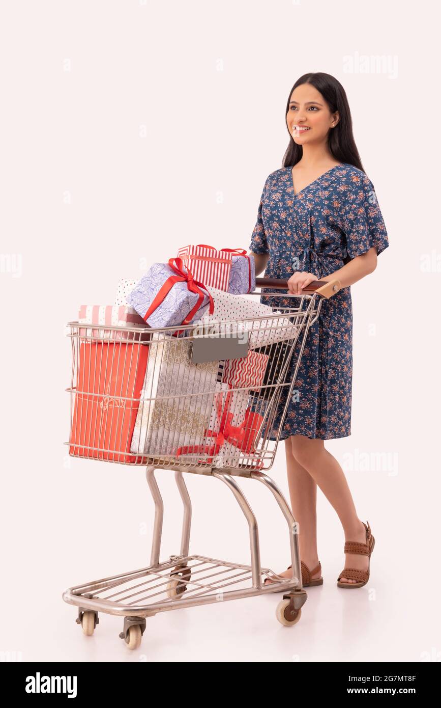 A young woman standing by her shopping cart full of gifts. Stock Photo