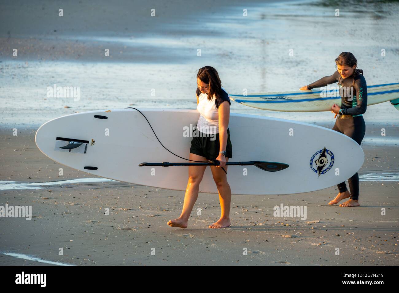 North Wildwood, United States. 15th July, 2021. Arianna Qira, 27 and Makenzie Franco, 27, of West Cape May exit the Atlantic Ocean after an early morning paddle board session on a warm summer day Thursday, July 15, 2021 at in North Wildwood, New Jersey. Temperatures are expected in the 90's through the rest of this week. Credit: William Thomas Cain/Alamy Live News Stock Photo