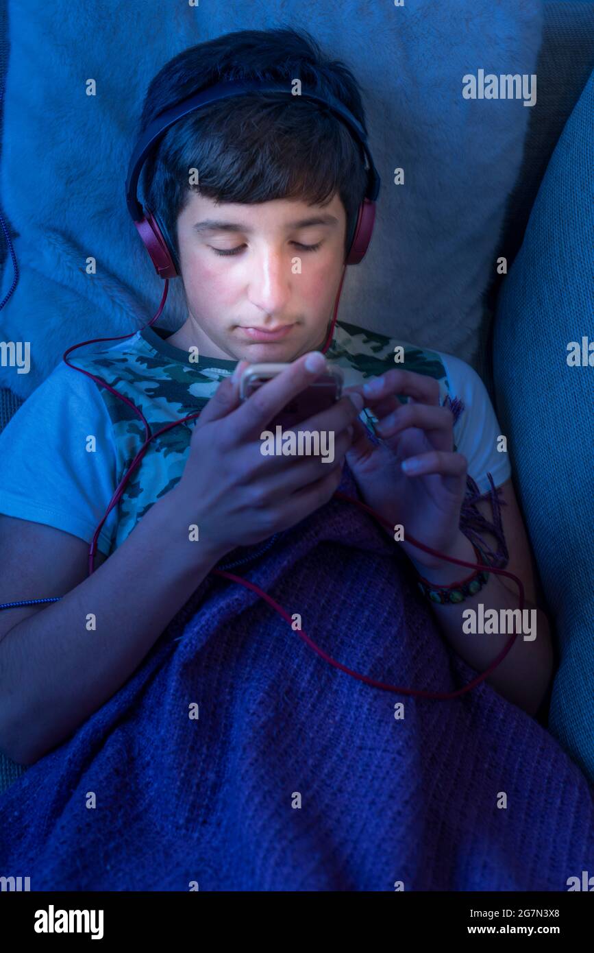 Teenage boy on his phone in bed,UK Stock Photo