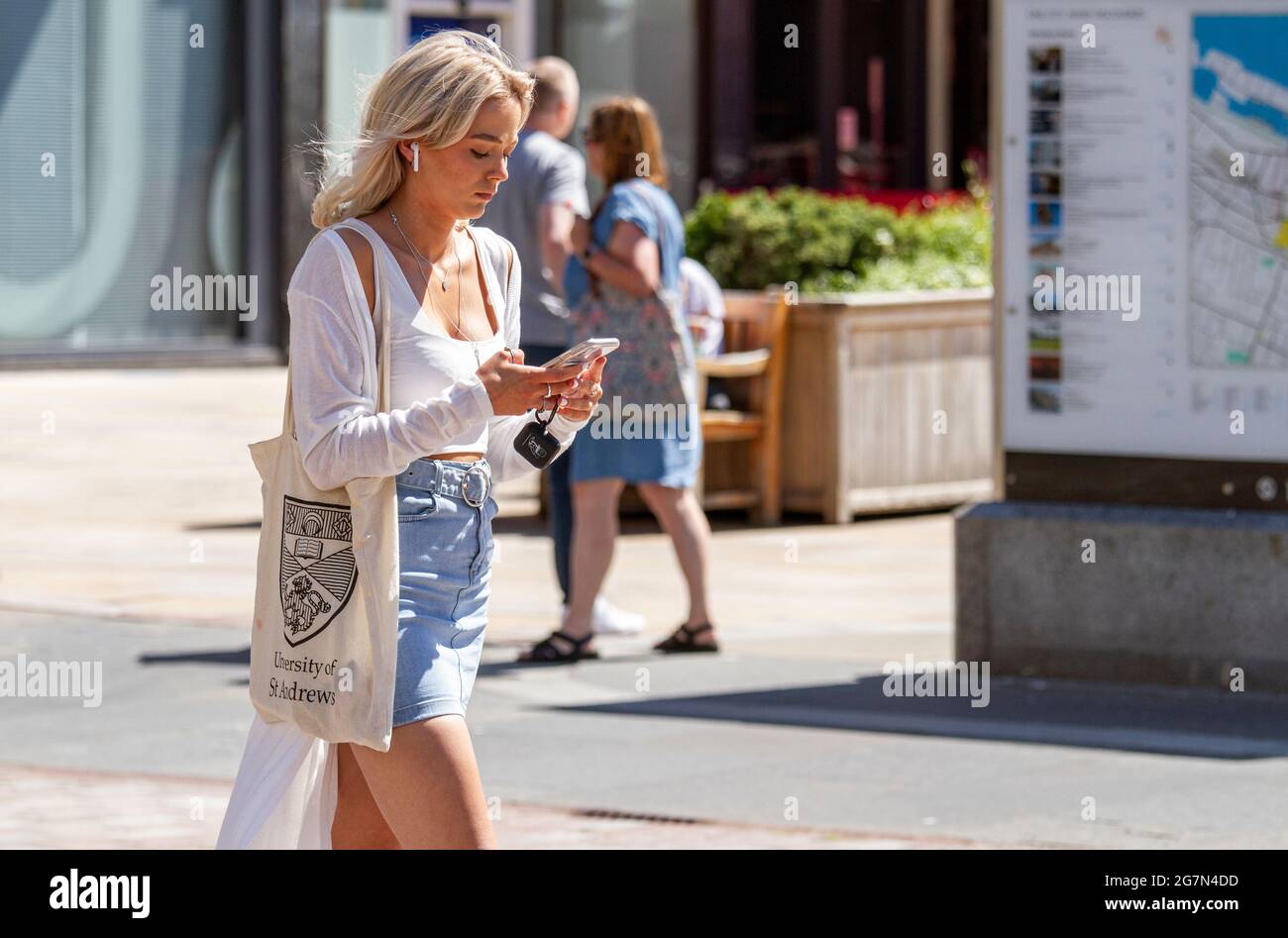 Dundee, Tayside, Scotland, UK. 15th July, 2021. UK Weather: Warm sunshine across North East Scotland with temperatures reaching 20°C. A young fashionable female St Andrews University student takes the day out to enjoy the Summer weather whilst texting messages on her I Phone in Dundee city centre. Credit: Dundee Photographics/Alamy Live News Stock Photo