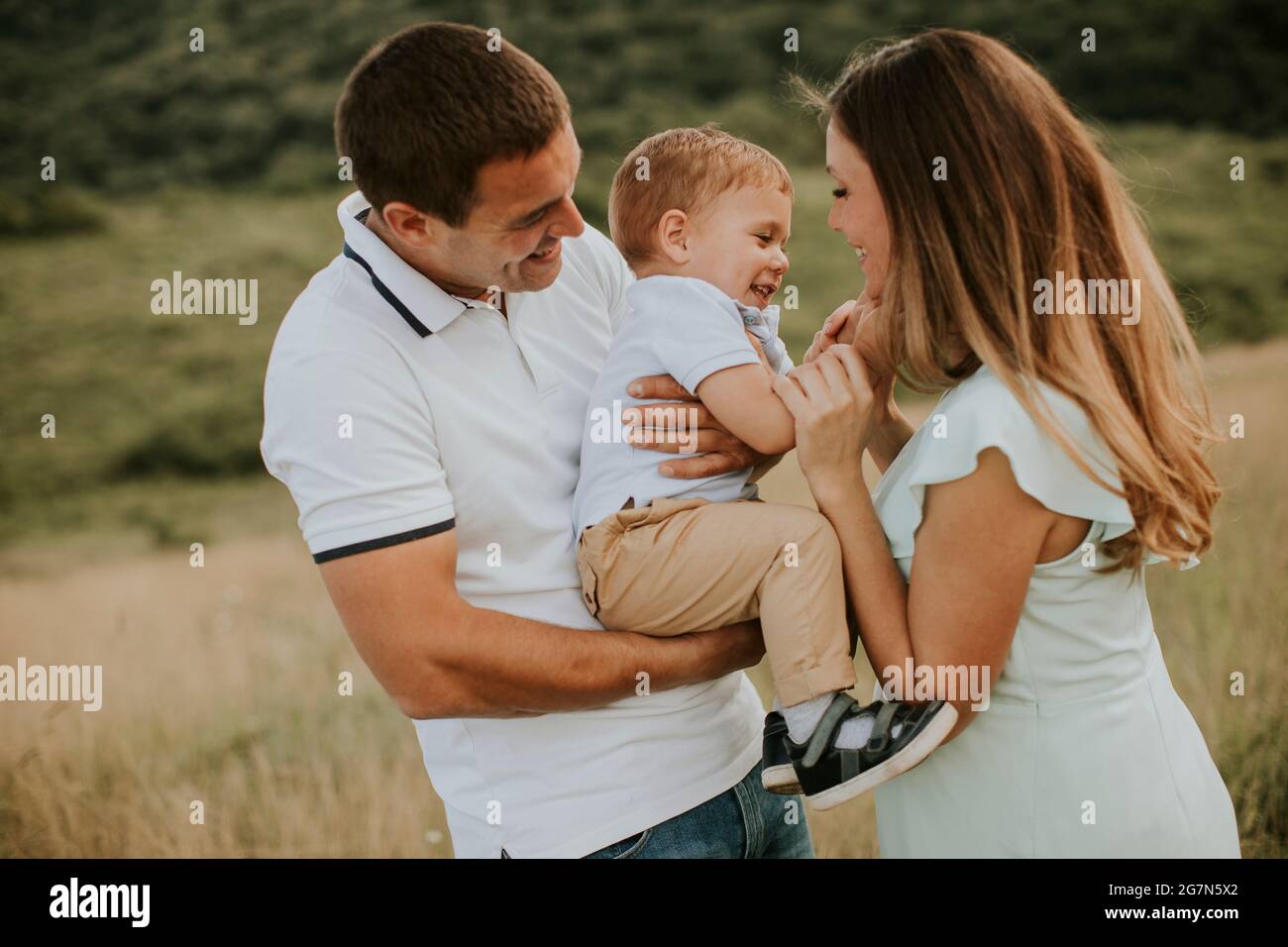 Young family with cute little boy having fun outdoors in the summer field Stock Photo