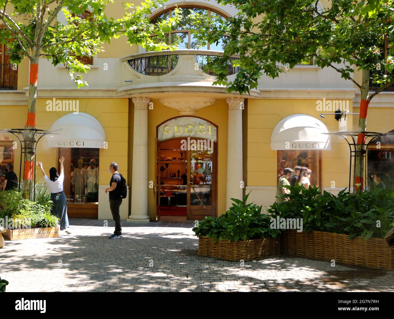Gucci shop front Las Rozas Shopping Mall Madrid Spain with a woman  stretching up towards water vapour dispensed for cooling in the heat Stock  Photo - Alamy