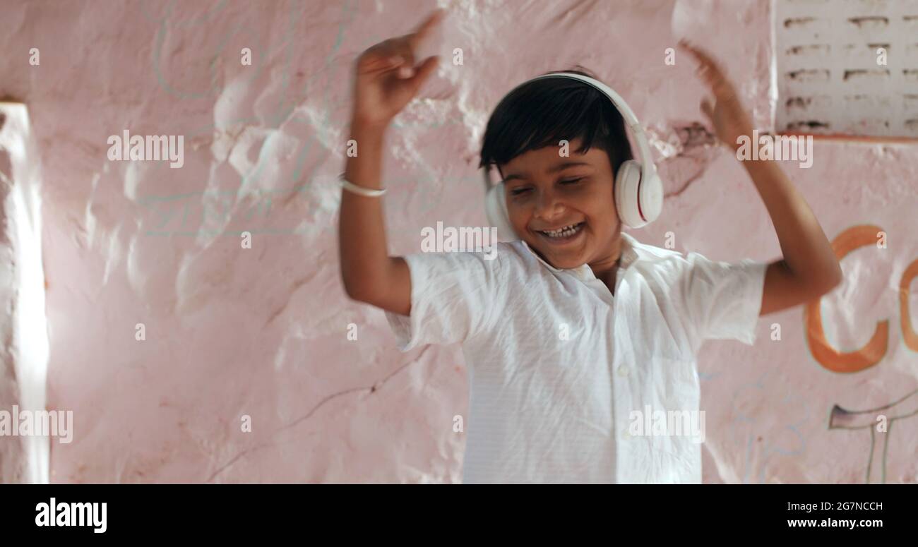 Joyful young Indian boy dancing carelessly while listening to music