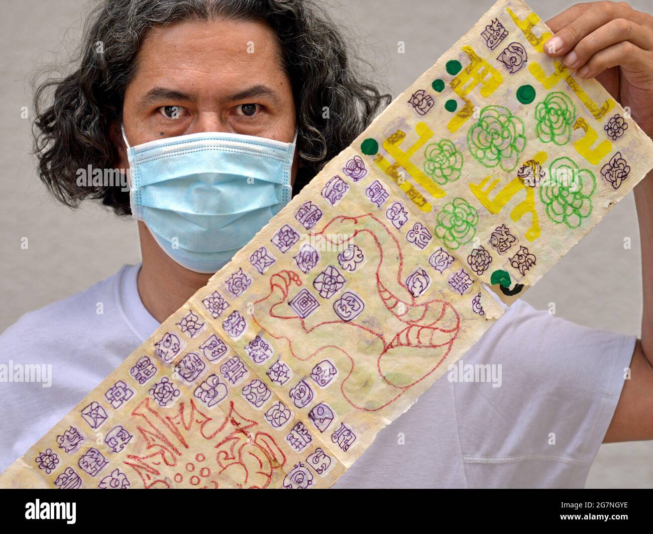 Mexican Yucatecan graphic artist and researcher of Maya history shows a hand-crafted and hand-painted leporello with Maya script (Maya glyphs). Stock Photo