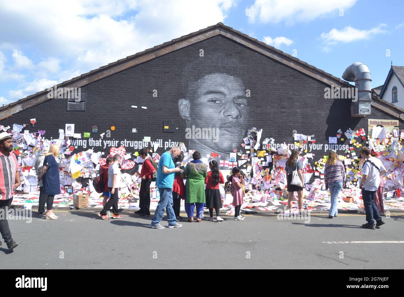 People leave flowers and hundreds of supportive notes, pictures, flags and anti racist messages on the giant  Manchester United player  Marcus Rashford mural in Withington, Manchester, England, United Kingdom, that was vandalised  with abusive graffiti after England's Euro2020 football loss on July 11th, 2021. The mural was created by French-born street artist Akse P19 on the wall of the Coffee House Cafe on Copson Street. Marcus Rashford is a Manchester United football player. Akse fully repaired the damaged mural by 13th July, 2021. Stock Photo