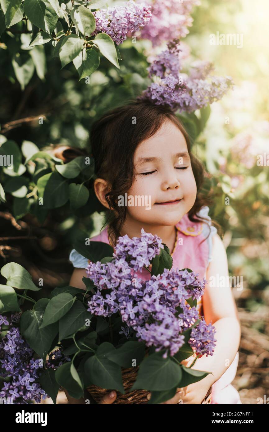 Vertical photo of little girl holding basket with blooming lilacs Stock ...