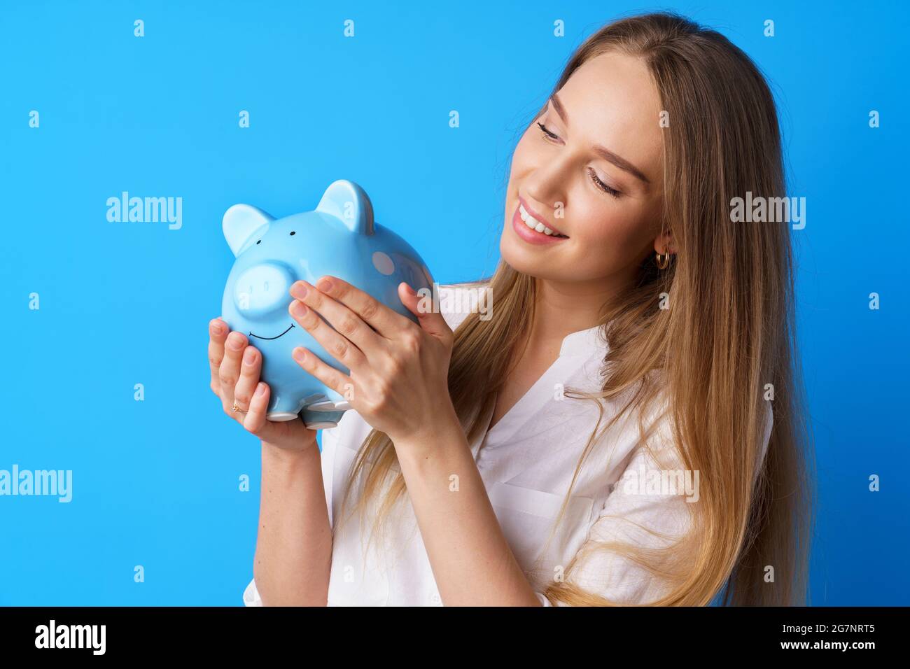 Beautiful smiling young woman with piggy bank on blue background Stock ...