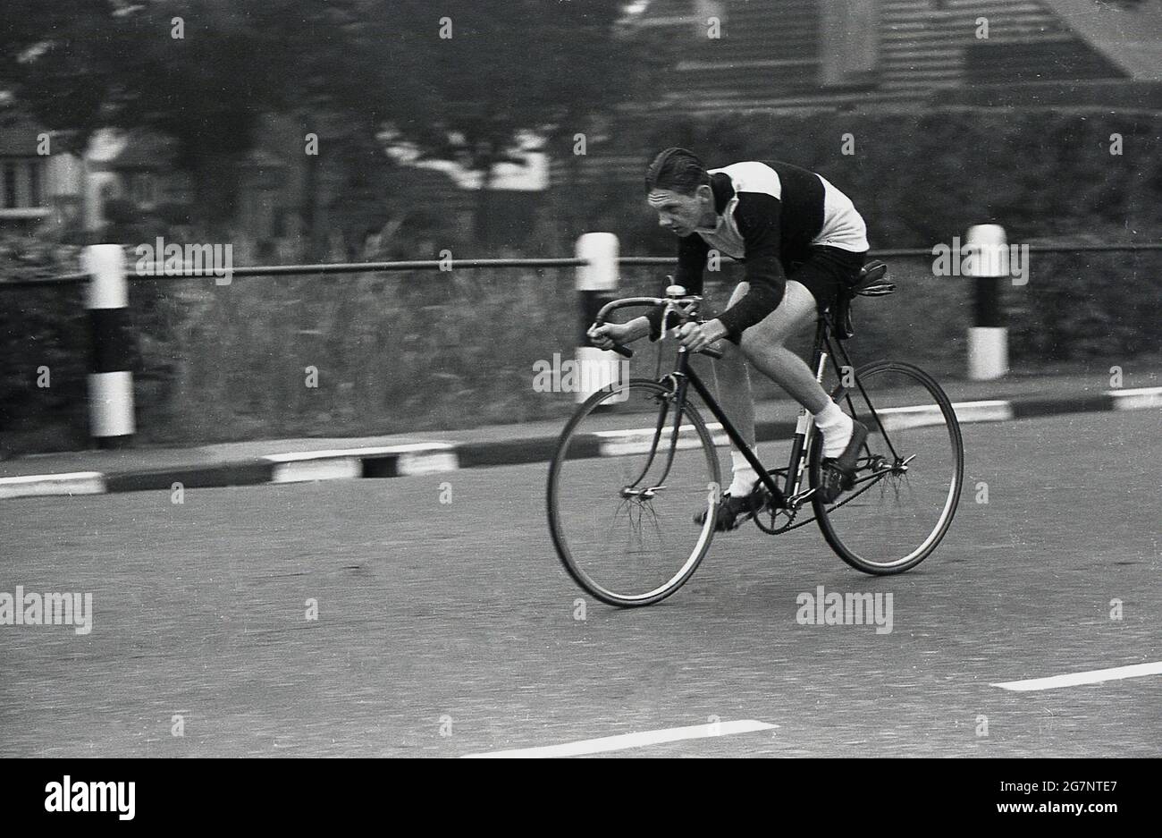 1950s, historical, head down, an amateur male cyclist in cycling clothes of the era, competing in a time-trial event on an urban, public road, Essex, England, UK. It can be see that he is riding a fixed-gear or fixed -wheel bicycle, with one brake to the front wheel only and the obligatory bell on the stem. Stock Photo