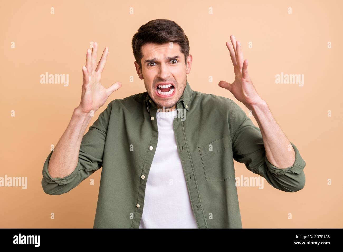 Photo of shocked aggressive young annoyed man raise hands bad mood isolated on beige color background Stock Photo