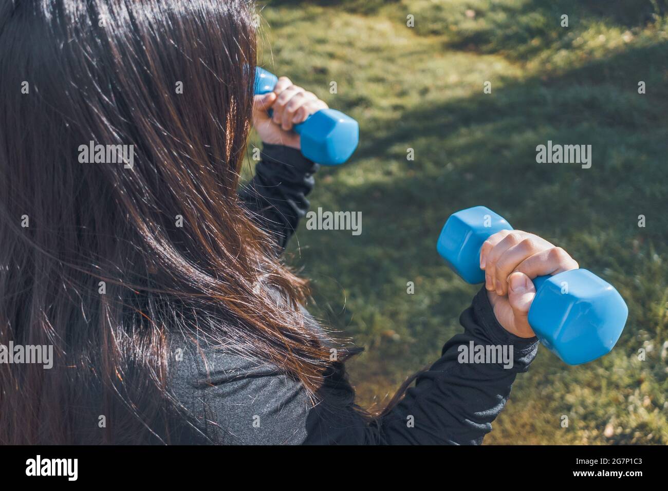 Plus size woman holding two blue dumbells. Healthy life. Fitness concept Stock Photo