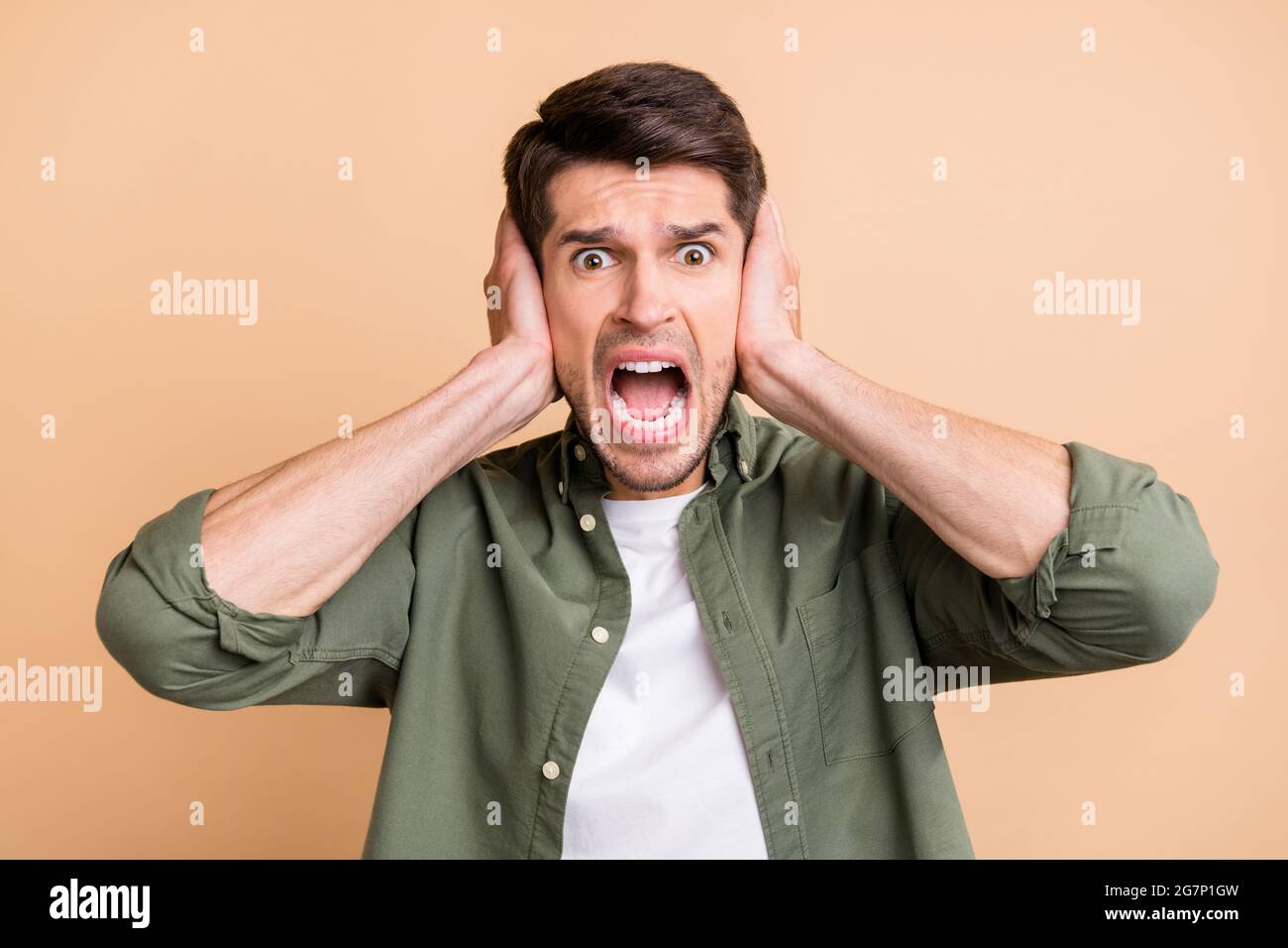 Photo of young amazed shocked afraid young man hold hands cover ears