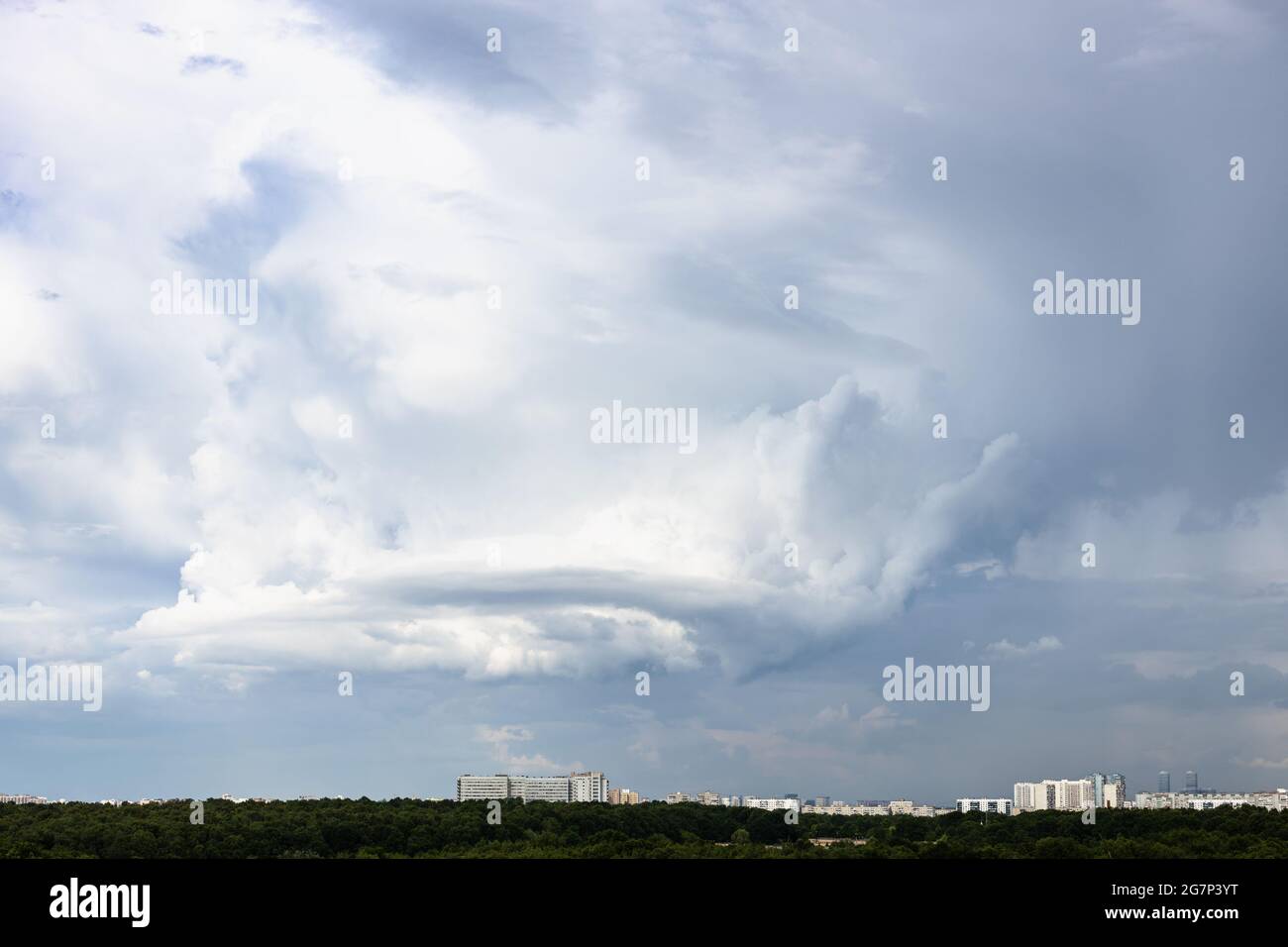 gray rainy clouds with whirls over city and forest on June day Stock Photo