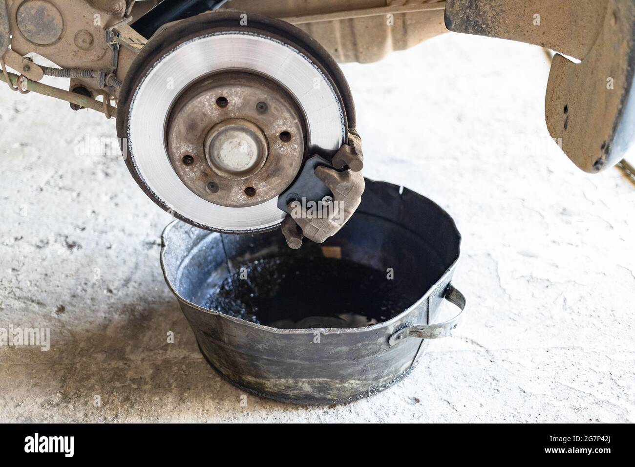 old brake fluid is drained into steel basin in rural car