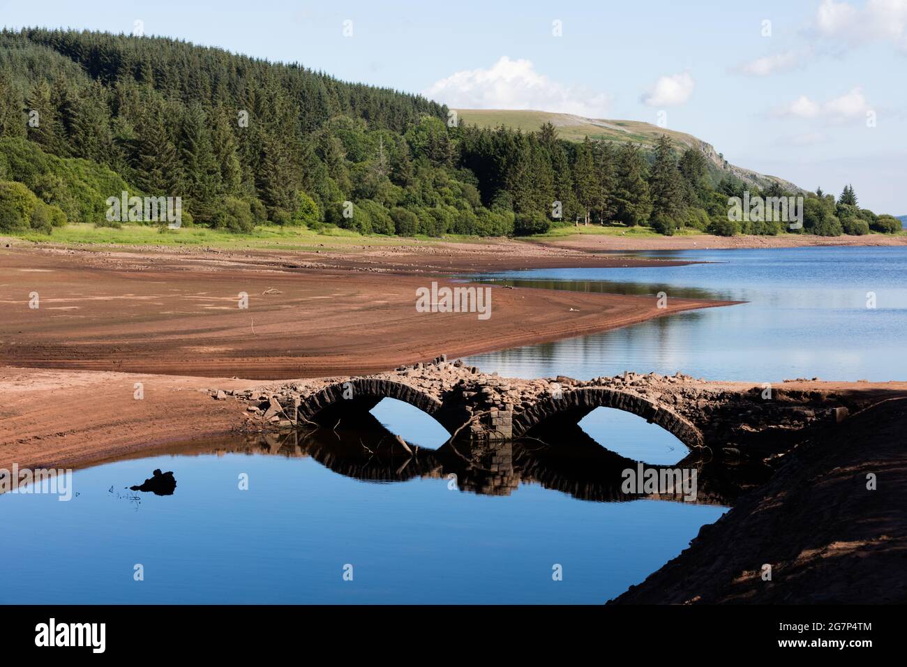 Llwyn Onn reservoir, Merthyr Tydfil, South Wales, UK.  15 July 2021.  UK weather:  Lower water levels than normal due to the heat, have uncovered Pont Yr Daf bridge, usually underwater.  It was built before the reservoir was constructed.  Credit: Andrew Bartlett/Alamy Live News Stock Photo
