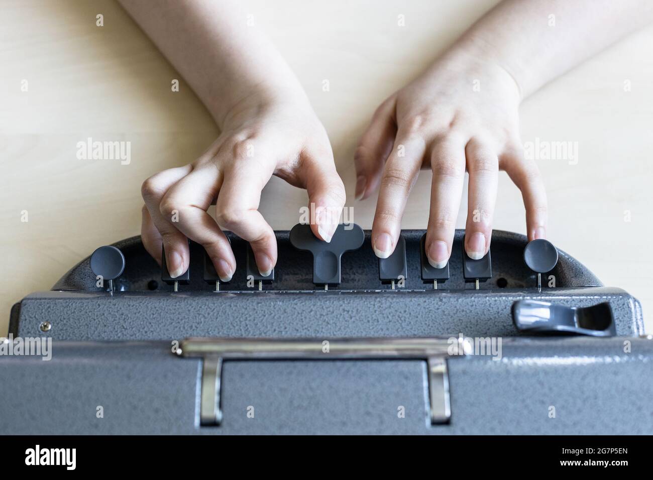 Moscow, Russia - June 5, 2021: top view of hands typing on Perkins Brailler typewriter. The first Perkins Brailler was produced in 1951 by David Abrah Stock Photo