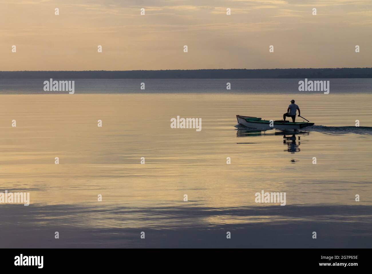 Scenic view of a man in the boat swimming peacefully on the water Stock