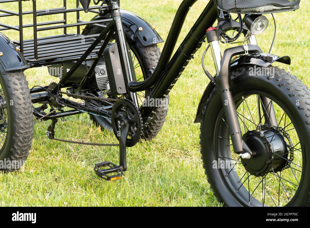 Electric trike or bicycle in the park in sunny summer day. Unfiltered, with natural lighting. E motor and power battery of the three wheel bike. Ecolo Stock Photo