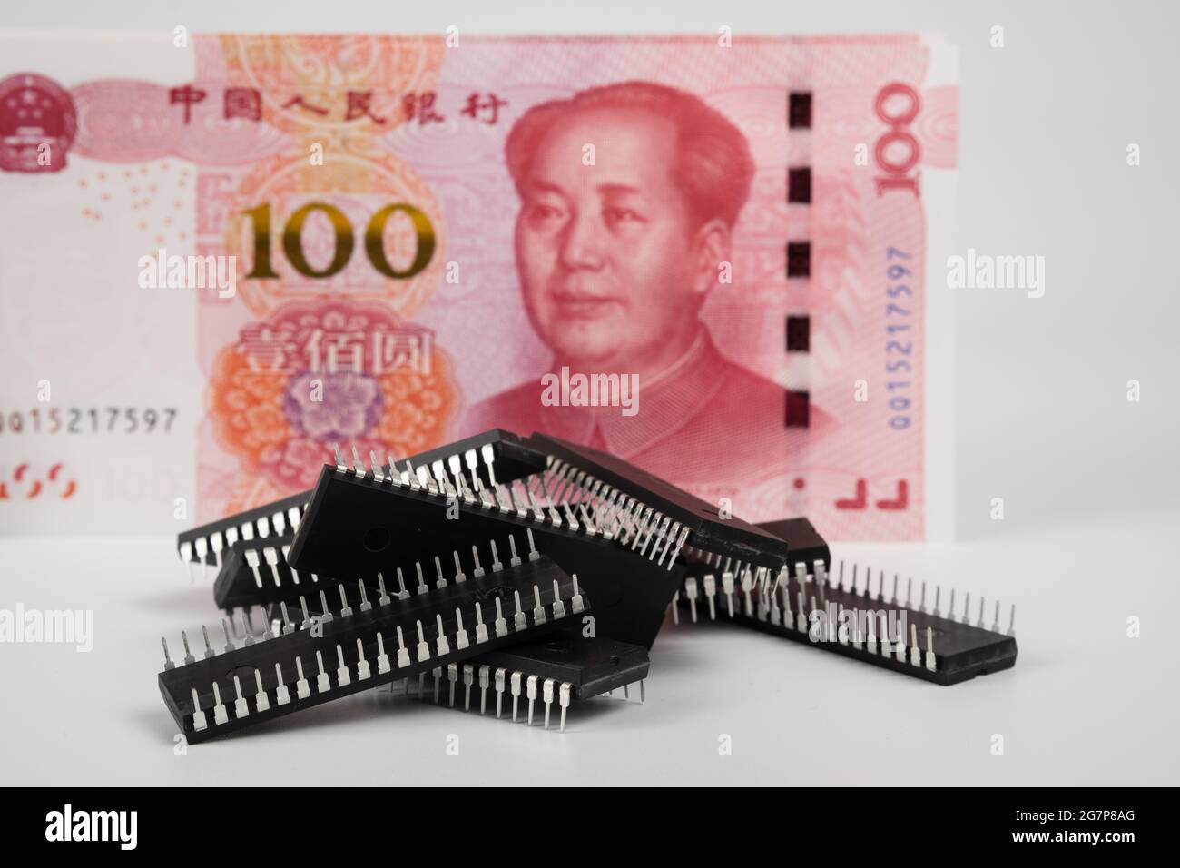 Pile of micro chips placed in front and banknotes of Chinese 100 Renminbi. Concept. Stock Photo