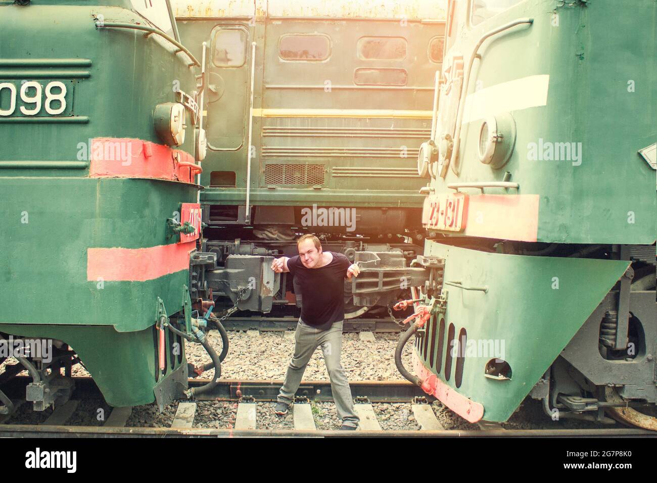 A man clamped in a Vice between two cars. Color photo of a man constrained by circumstances. The guy on the tracks is trapped by machinery. Stock Photo