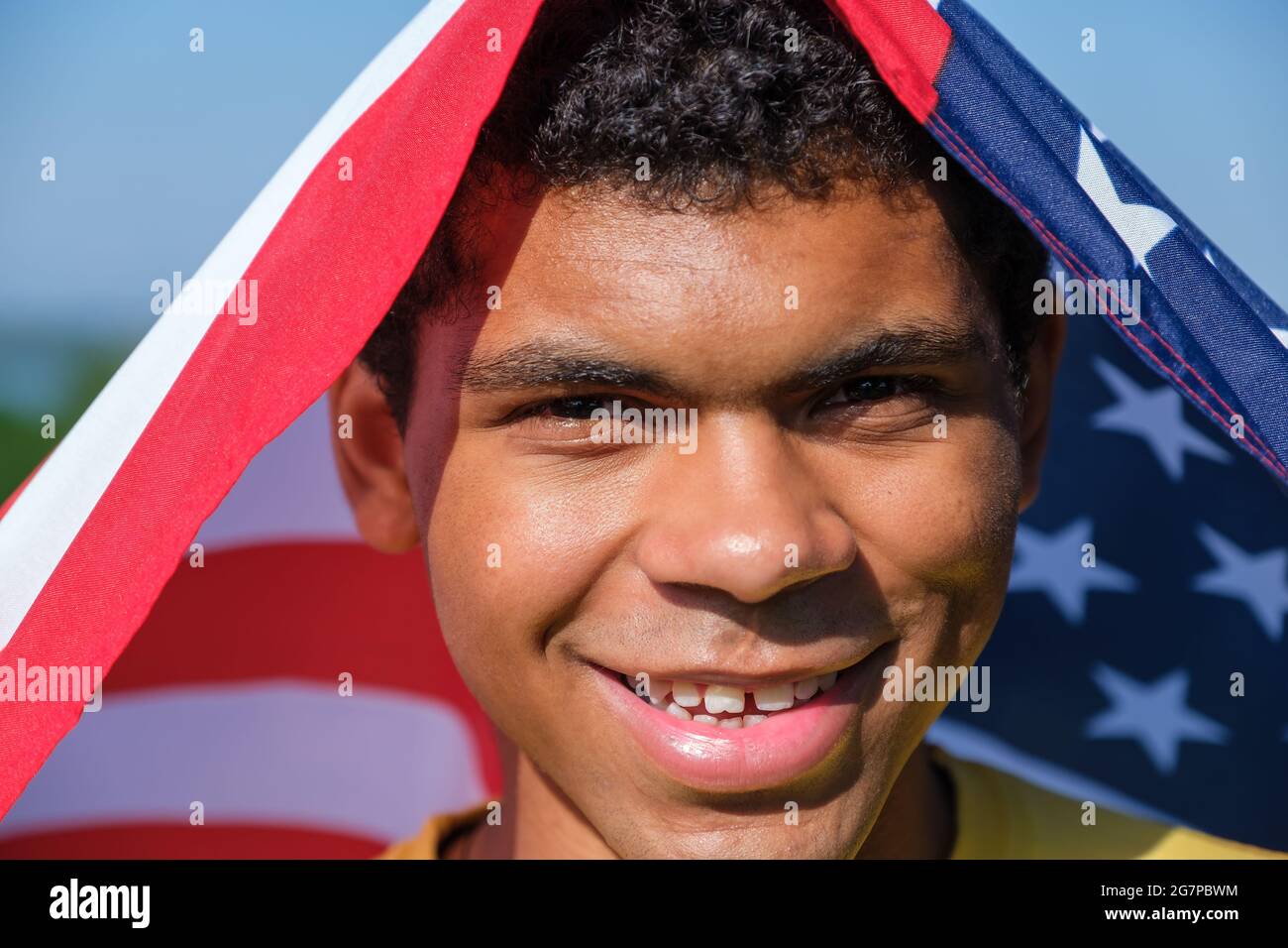 Closeup face of happy AfricanAmerican man wraps himself in the U.S