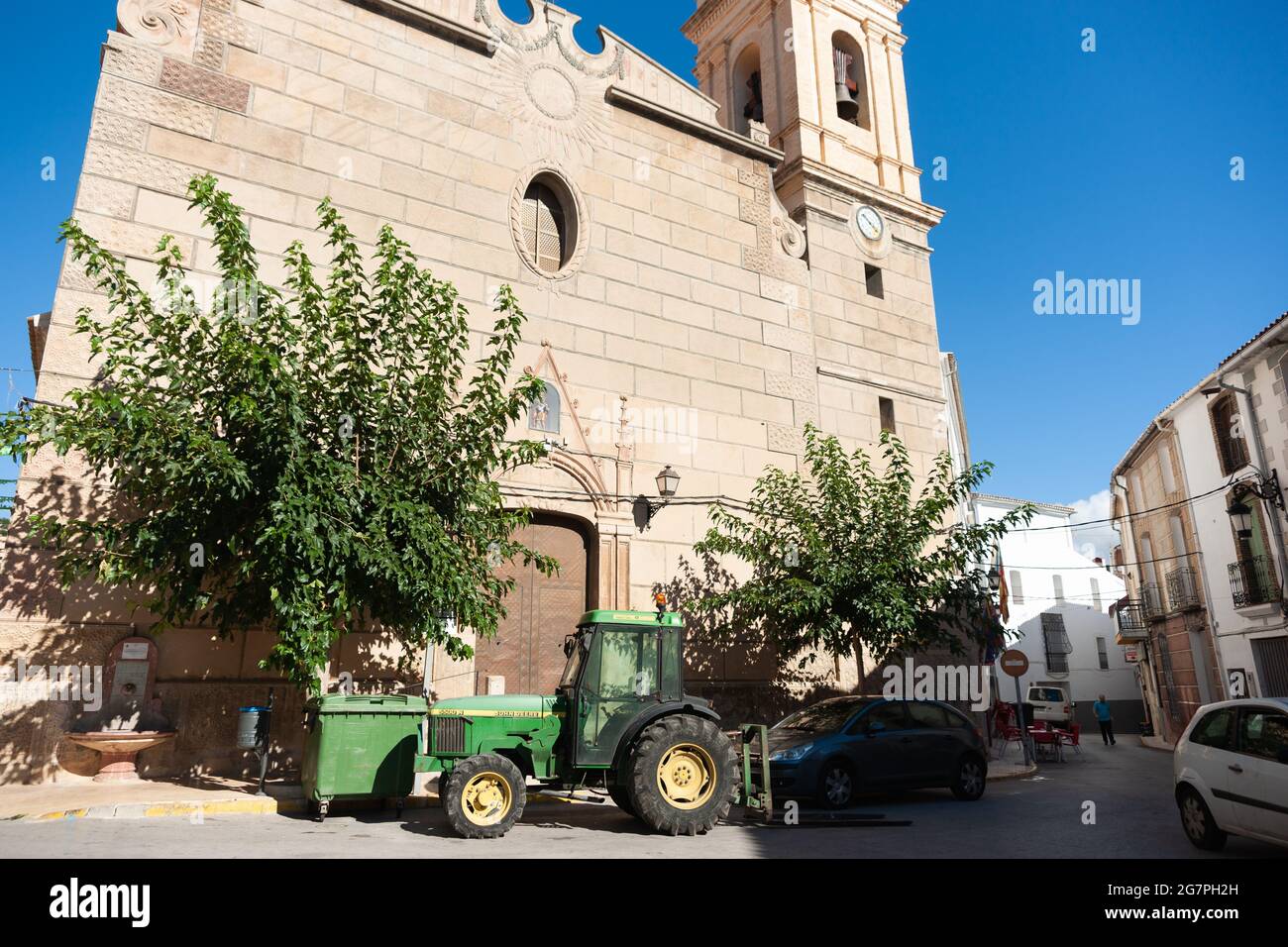 Tarbena Spain - August 26 2016; Green John Deere tractor parked in narrow village street outside church of Saint Barbara. Stock Photo