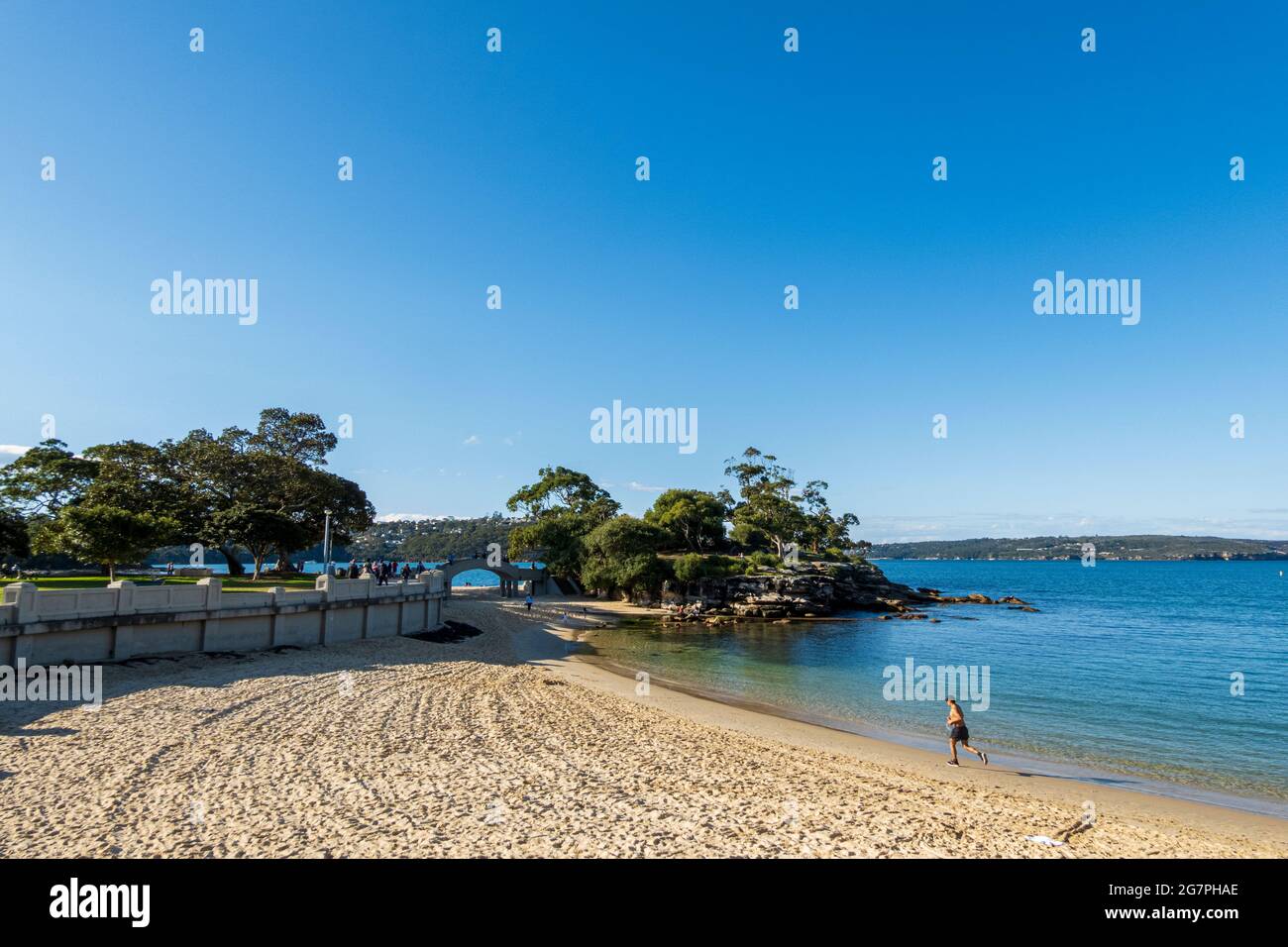 Man running at Balmoral Beach, Sydney, Australia, on a sunny day during pandemic lockdown. Longshot of beach and sky. Stock Photo