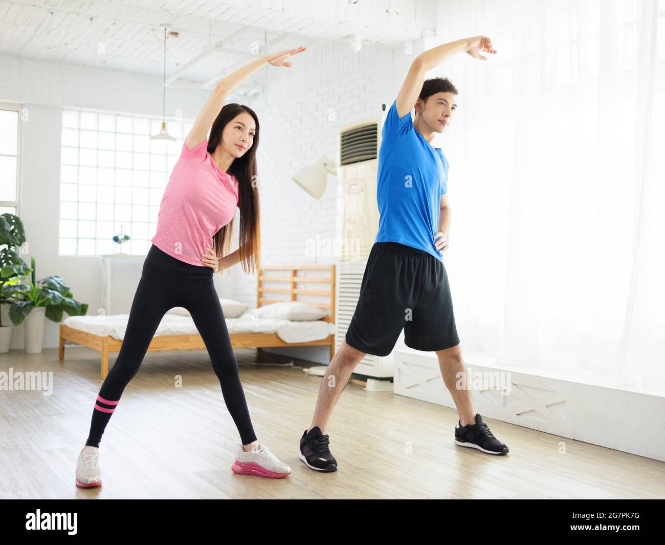 Young couple doing  lateral flexion exercise at home. Stock Photo