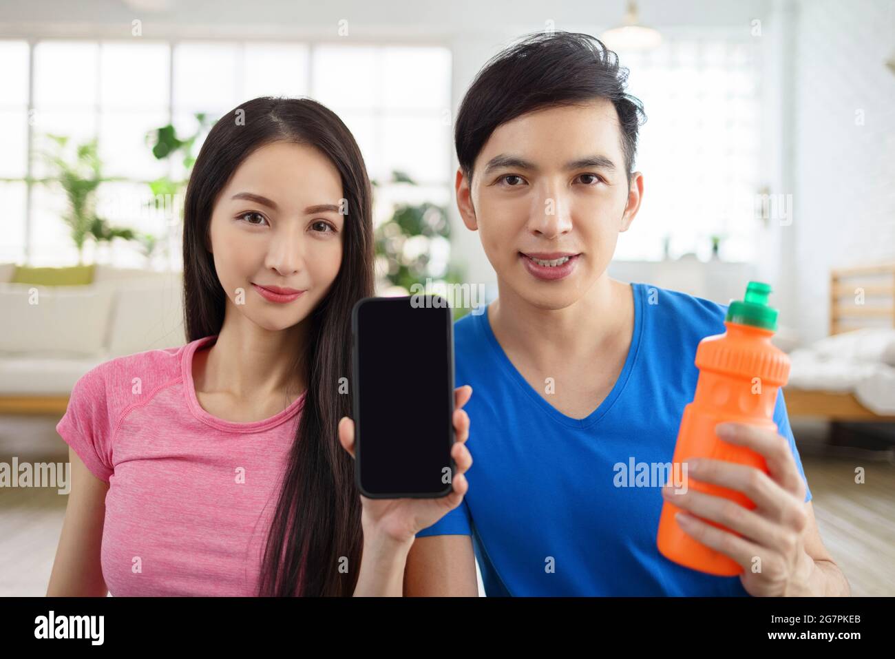 couple  showing smartphone with empty screen at home. Stock Photo
